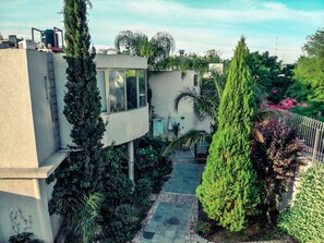 A modern building with a curved facade, surrounded by lush greenery and a paved pathway. - Exclusive full department - Avenida Emilio Civit 157 (Mendoza)