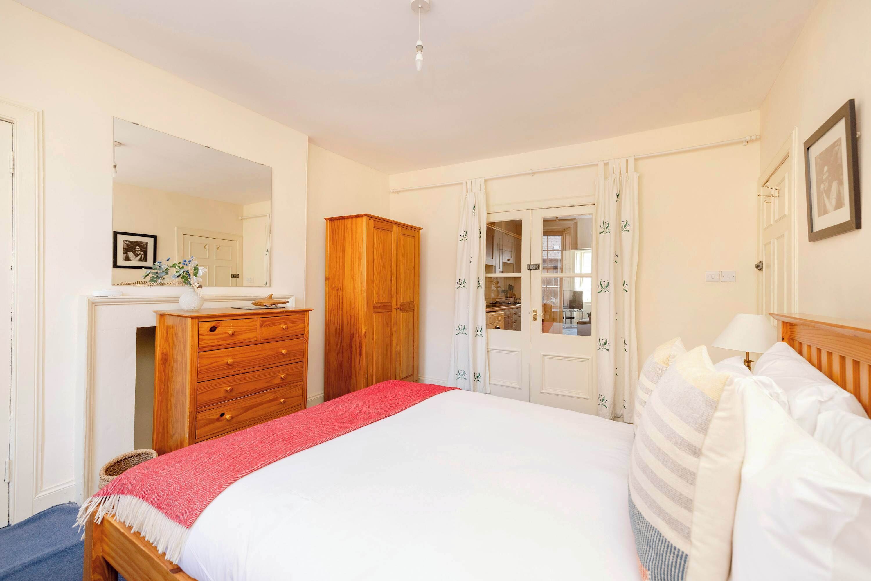 Une chambre à coucher comprenant un lit, une armoire en bois, une commode et un miroir.