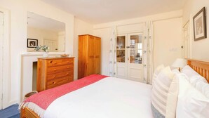 Un dormitorio con cama, armario de madera, cómoda y espejo.