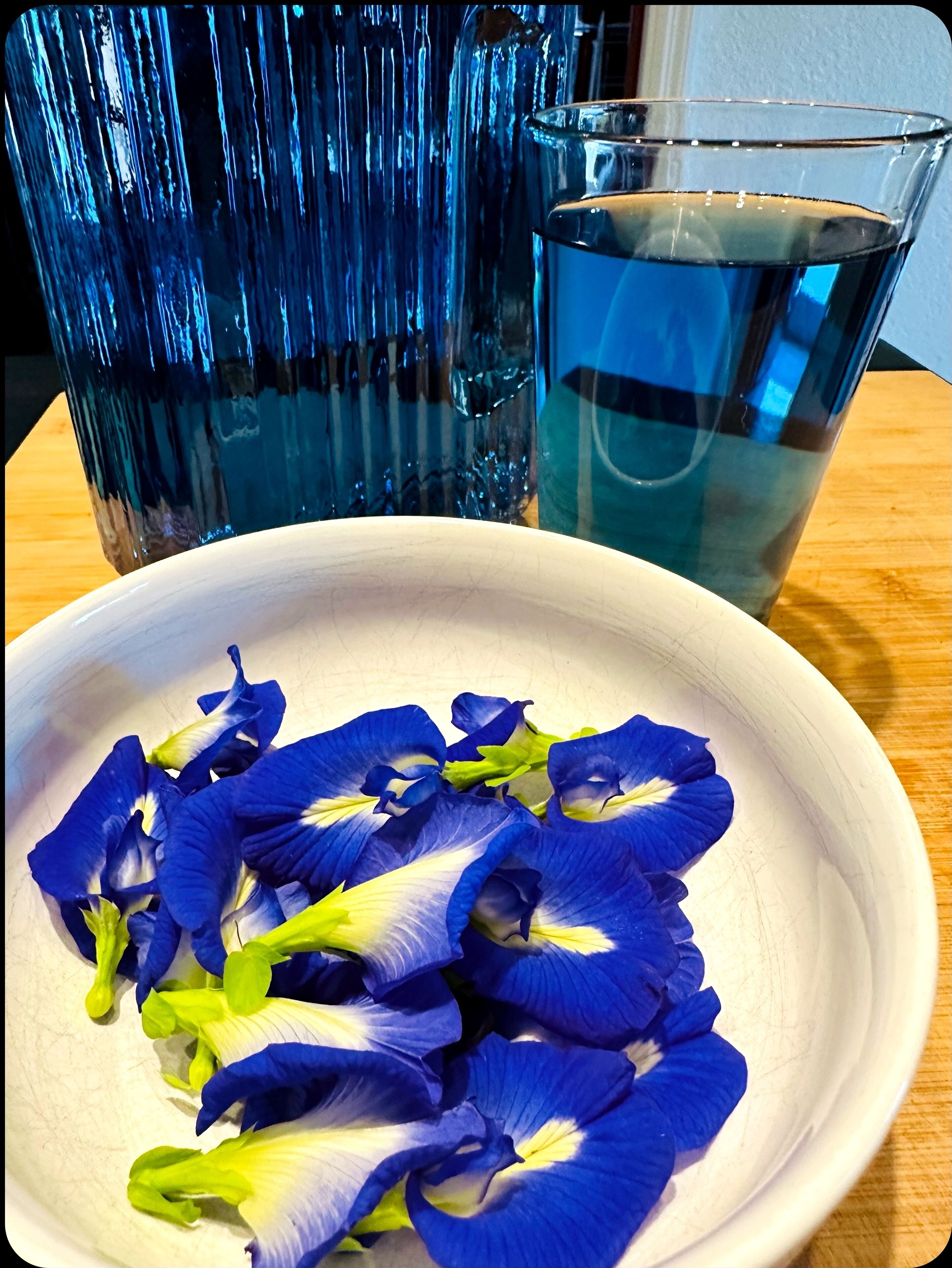 A bowl of blue and white flower petals on a table.