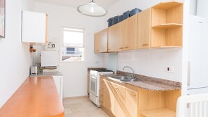 A modern kitchen with wooden cabinets, a granite countertop, a stove, and a sink.