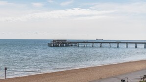 A beach with a pier extending into calm waters.