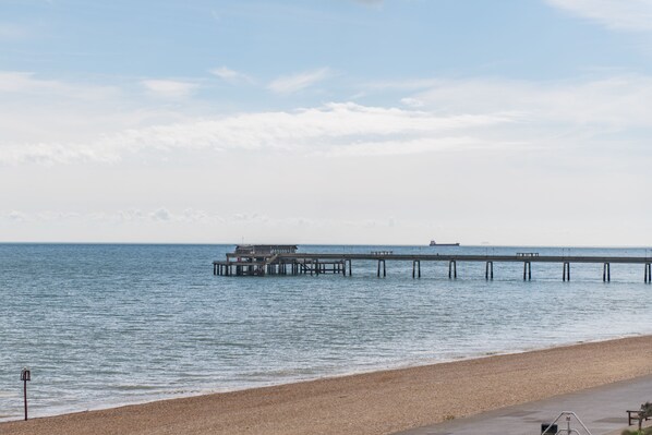 A beach with a pier extending into calm waters.