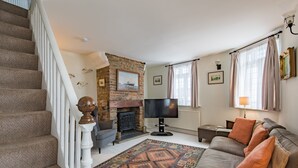 A living room with a fireplace, a sofa, a TV, and a staircase.