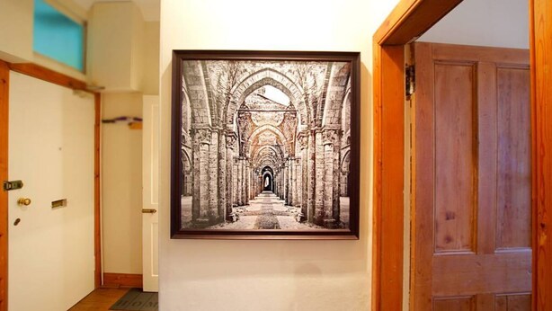 A hallway with a framed artwork of an ancient architectural corridor. - Castle View Vintage Retreat (Edinburgh)