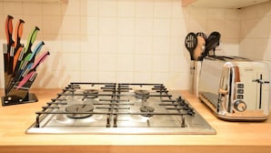 A kitchen with a gas stove, toaster, and utensil holder. - Castle View Vintage Retreat (Edinburgh)