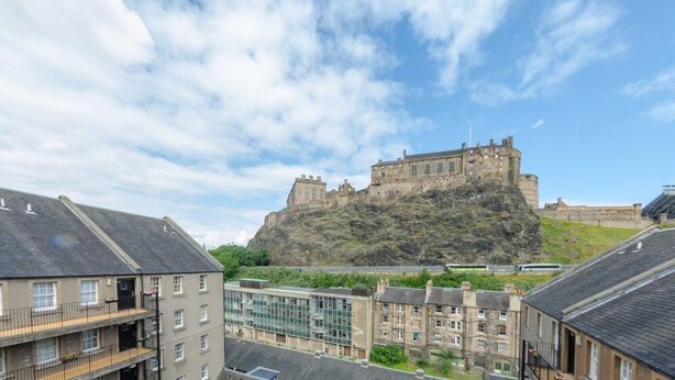Un château perché sur une colline, avec des immeubles résidentiels au premier plan.