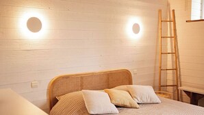 A bedroom with a checkered bedspread, two pillows, a wooden headboard, and two round wall sconces. - In the heart of "Cancale"  garden , 500m sea / garage (Cancale)