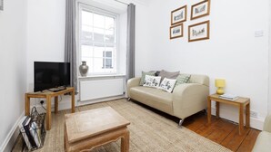 A living room with a sofa, a coffee table, a TV, and framed pictures on the wall.
