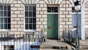 A building with a brick facade, a green door, and a black metal railing.