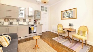 A modern kitchen with a dining area, a sofa, and a small table.