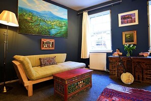 A cozy living room with a sofa, a coffee table, and a large painting on the wall. - Vibrant Edinburgh Flat with Private Entrance (Edinburgh)