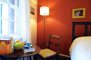 A hotel room with a bed, a table with a bowl of fruit, a lamp, and a chair. - Vibrant Edinburgh Flat with Private Entrance (Edinburgh)