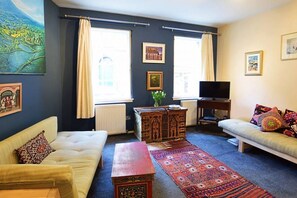 A living room with a sofa, a coffee table, a TV, and a patterned rug. - Vibrant Edinburgh Flat with Private Entrance (Edinburgh)