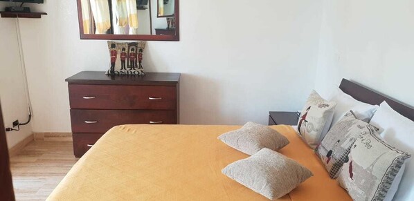 A bedroom with a bed, a dresser, and a mirror.