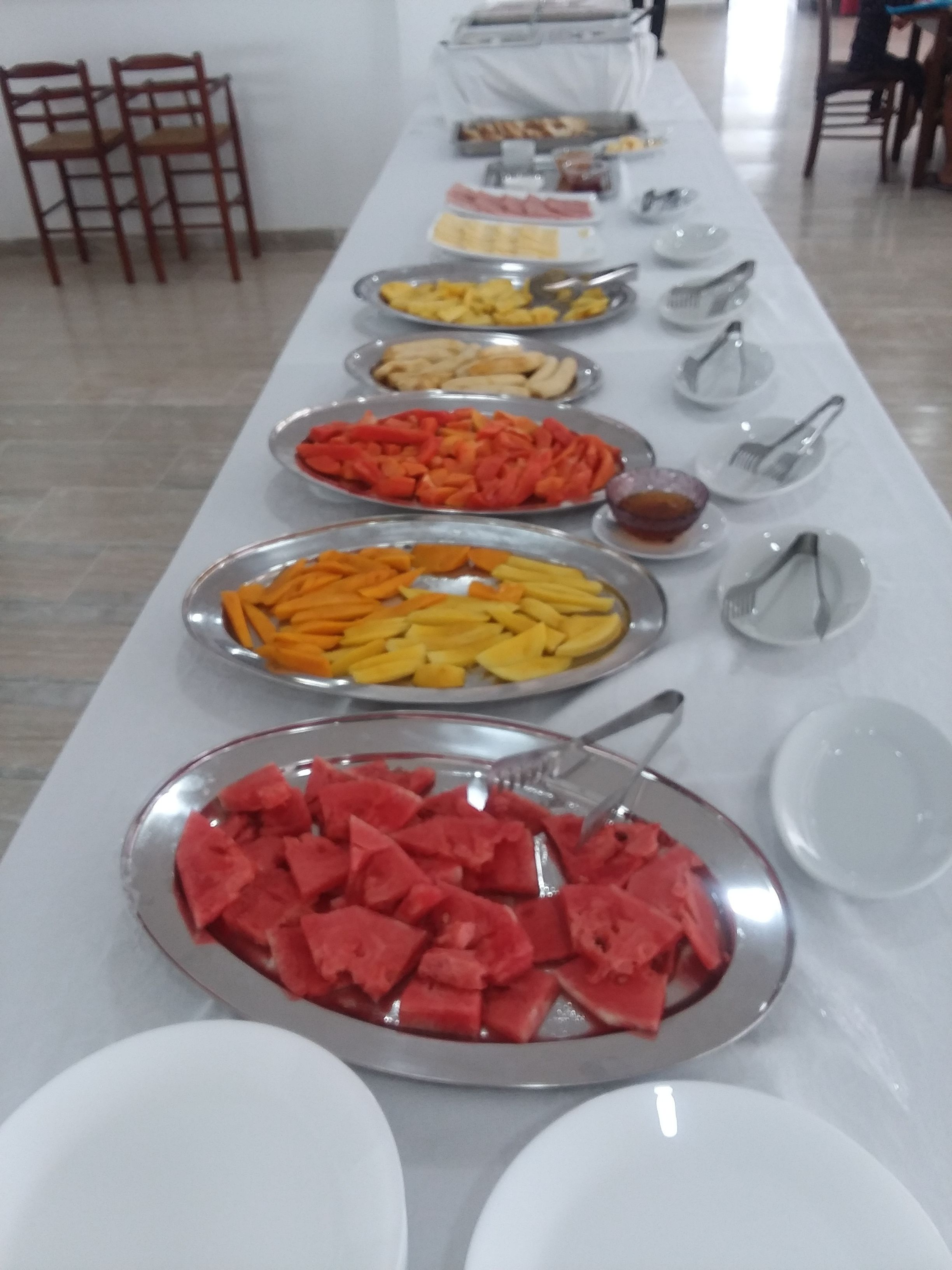 Una mesa de buffet con distintos alimentos y utensilios.