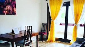 Un coin repas avec une table et des chaises en bois, un canapé et des rideaux jaunes.