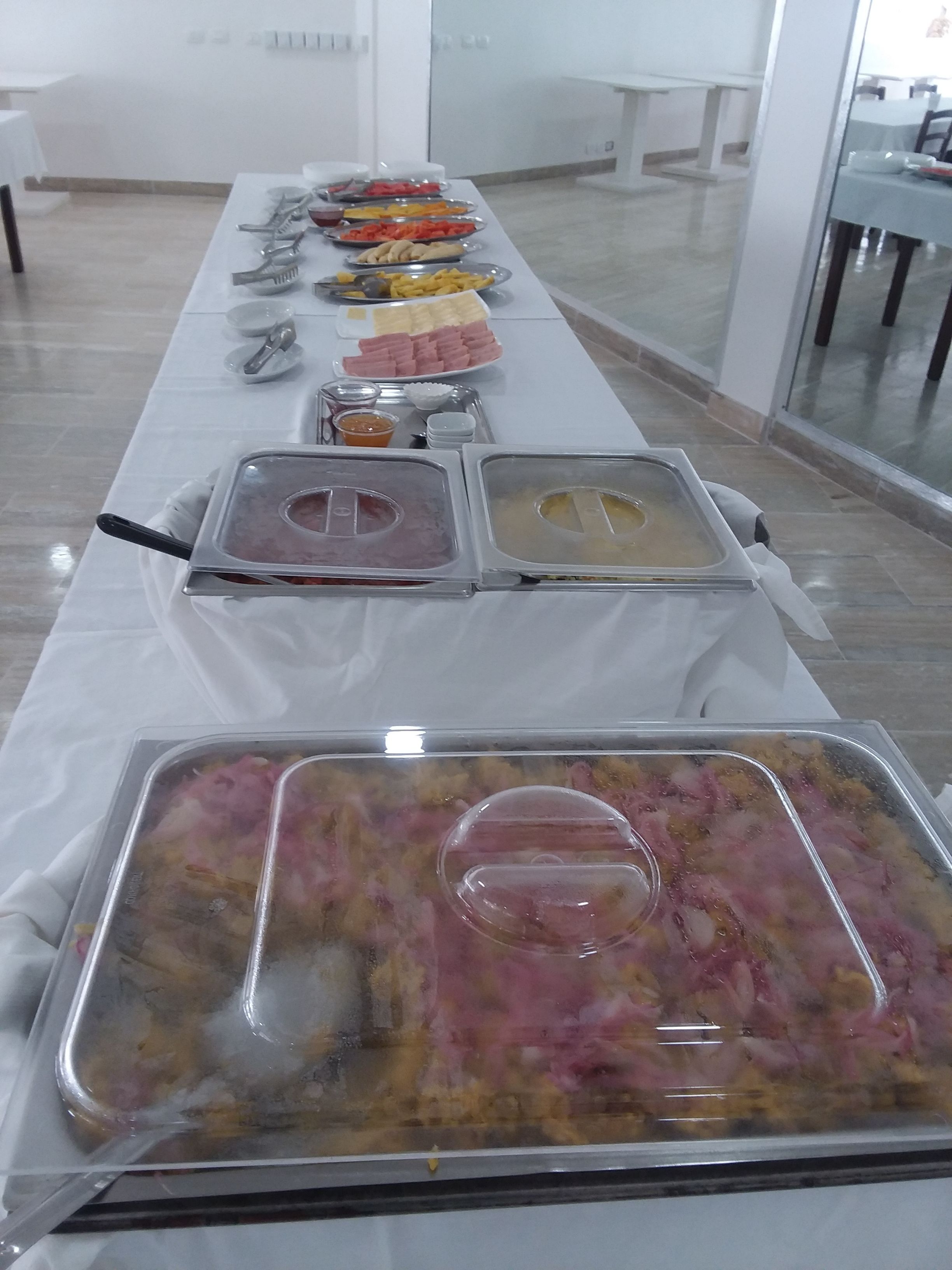 A buffet setup with various food items and utensils on a long table.