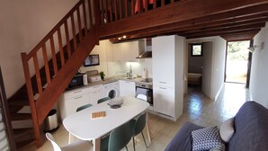 A modern kitchen with white cabinets, a dining table, and a staircase leading to an upper level.