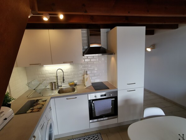 Una cucina moderna con forno integrato, lavello in acciaio inossidabile e mobili bianchi.