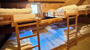 Una cabaña de madera con literas, una ventana y techo de madera.