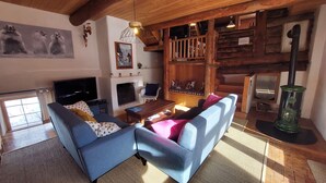 Una sala de estar acogedora con un sofá azul, una chimenea, un televisor y una escalera de madera.