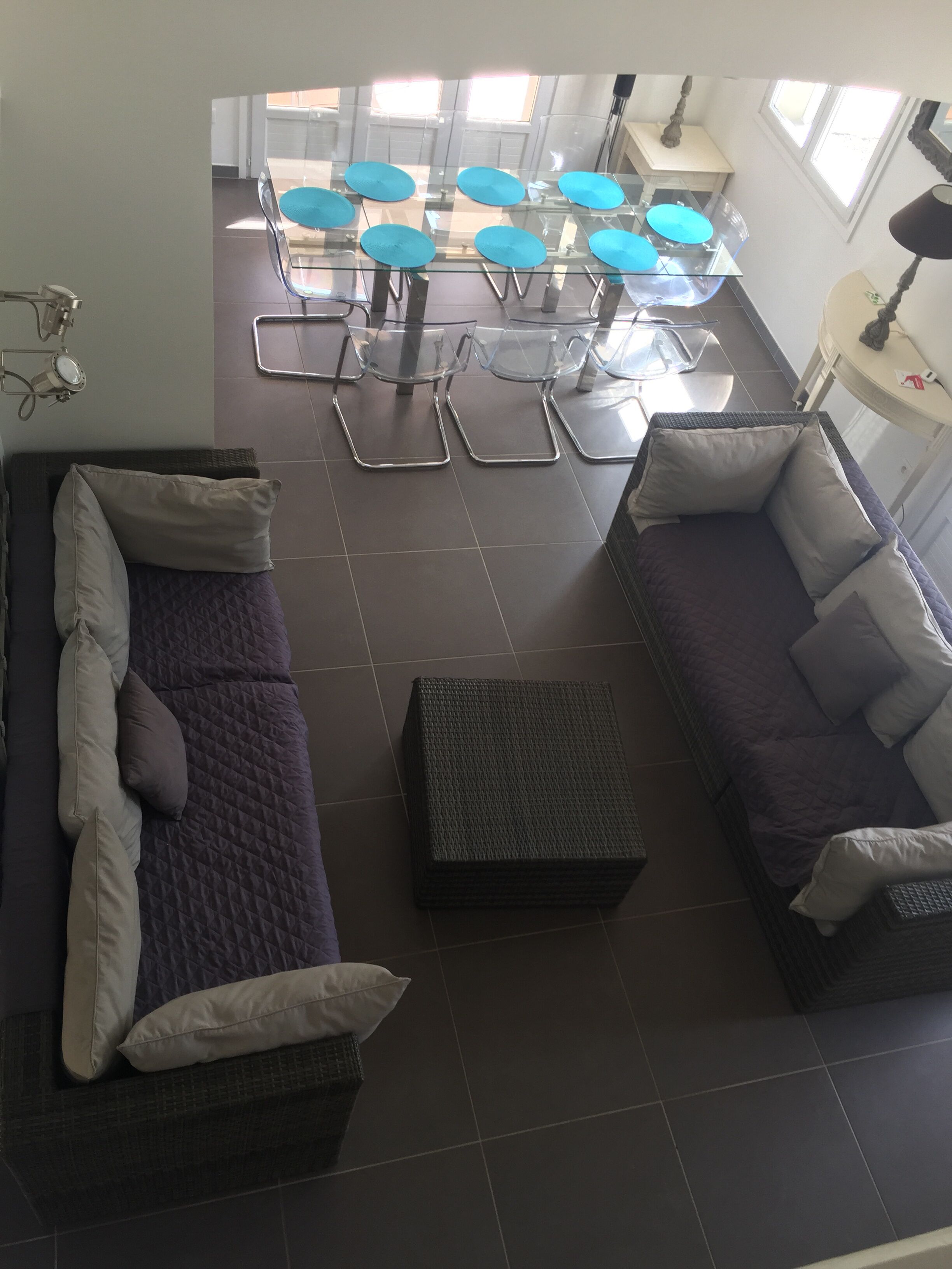 A modern living area with two sofas, a coffee table, and a dining table with blue chairs.