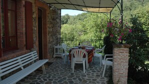 Eine Terrasse mit Tisch, Stühlen und einer Bank, daneben eine Ziegelmauer.