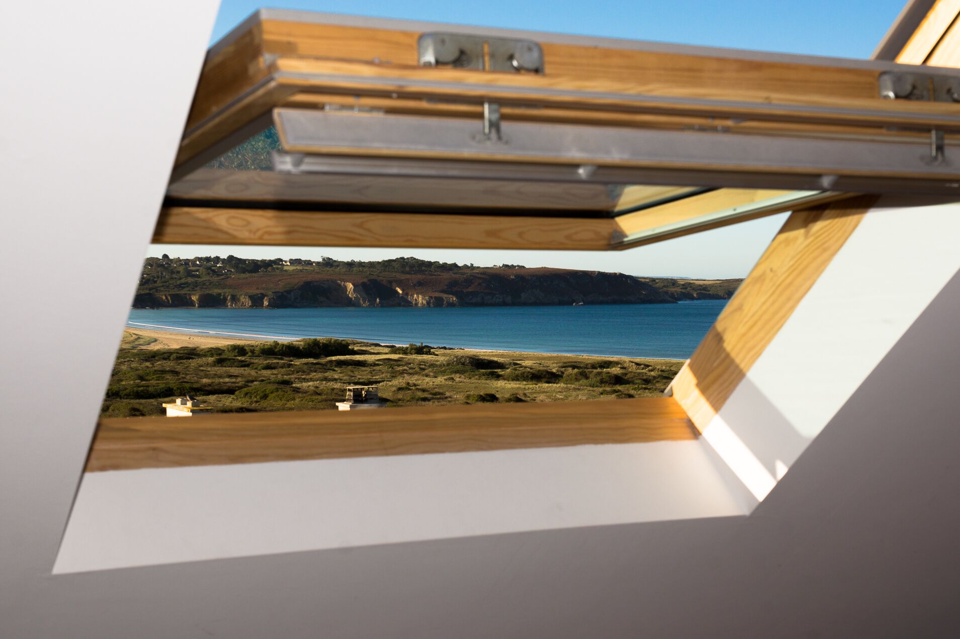 A view through a skylight of a coastal landscape with cliffs and a beach.