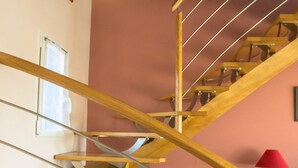Una scala a chiocciola in legno con ringhiere in metallo, una lampada rossa e una pianta in vaso rosso.