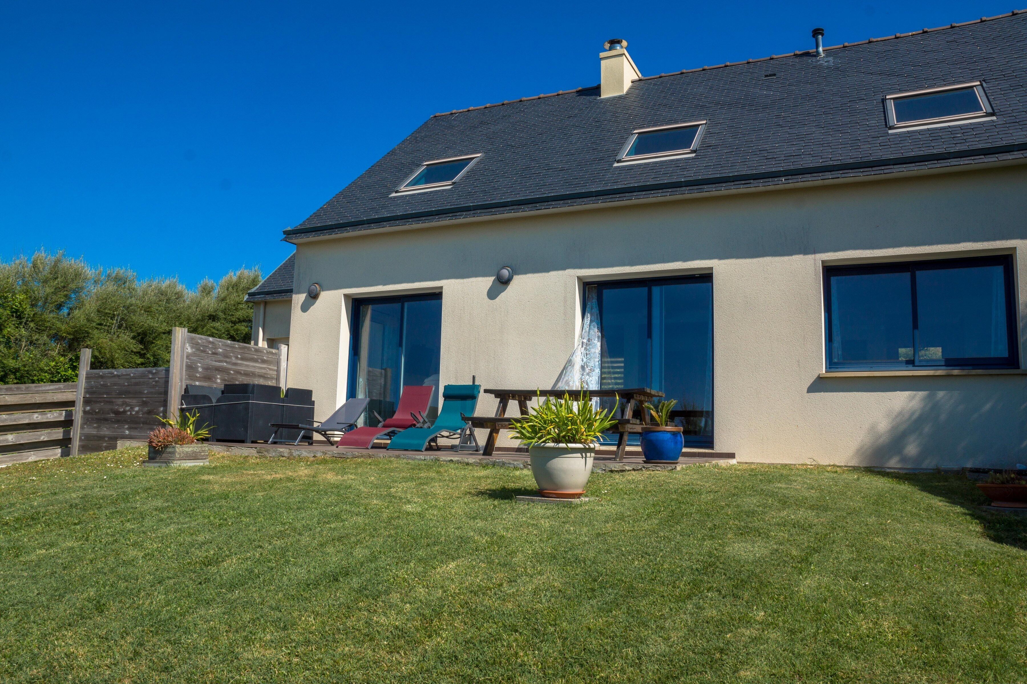 A modern house with a sloped roof, large windows, and a well-maintained lawn.