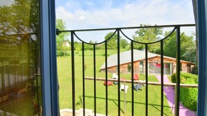 A view through a window with a metal railing, a grassy yard, a wooden cabin, and a clear sky. - Rental bed and breakfast and gite in Lignieres 18160 (Lignières)
