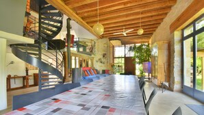 A spacious room with a long table, a spiral staircase, and large windows. - Rental bed and breakfast and gite in Lignieres 18160 (Lignières)