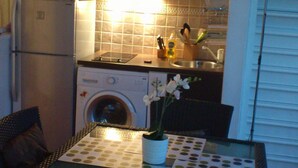 A compact kitchen with a microwave, oven, and washing machine. There's a dining table with a polka dot tablecloth and a potted plant. - Promotions 280th week Beautiful apartment StFrançois Domaine Anse des Rocher (97180)