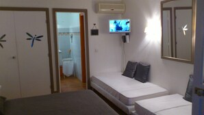 A bedroom with two beds, a television on the wall, and a bathroom visible through an open door. - Promotions 280th week Beautiful apartment StFrançois Domaine Anse des Rocher (97180)