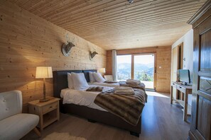 A wooden cabin bedroom with two beds, a TV, and a view of the mountains. - La Marcairie Grand Chalet - Spa Luxury 5 stars (Muhlbach-Sur-Munster)