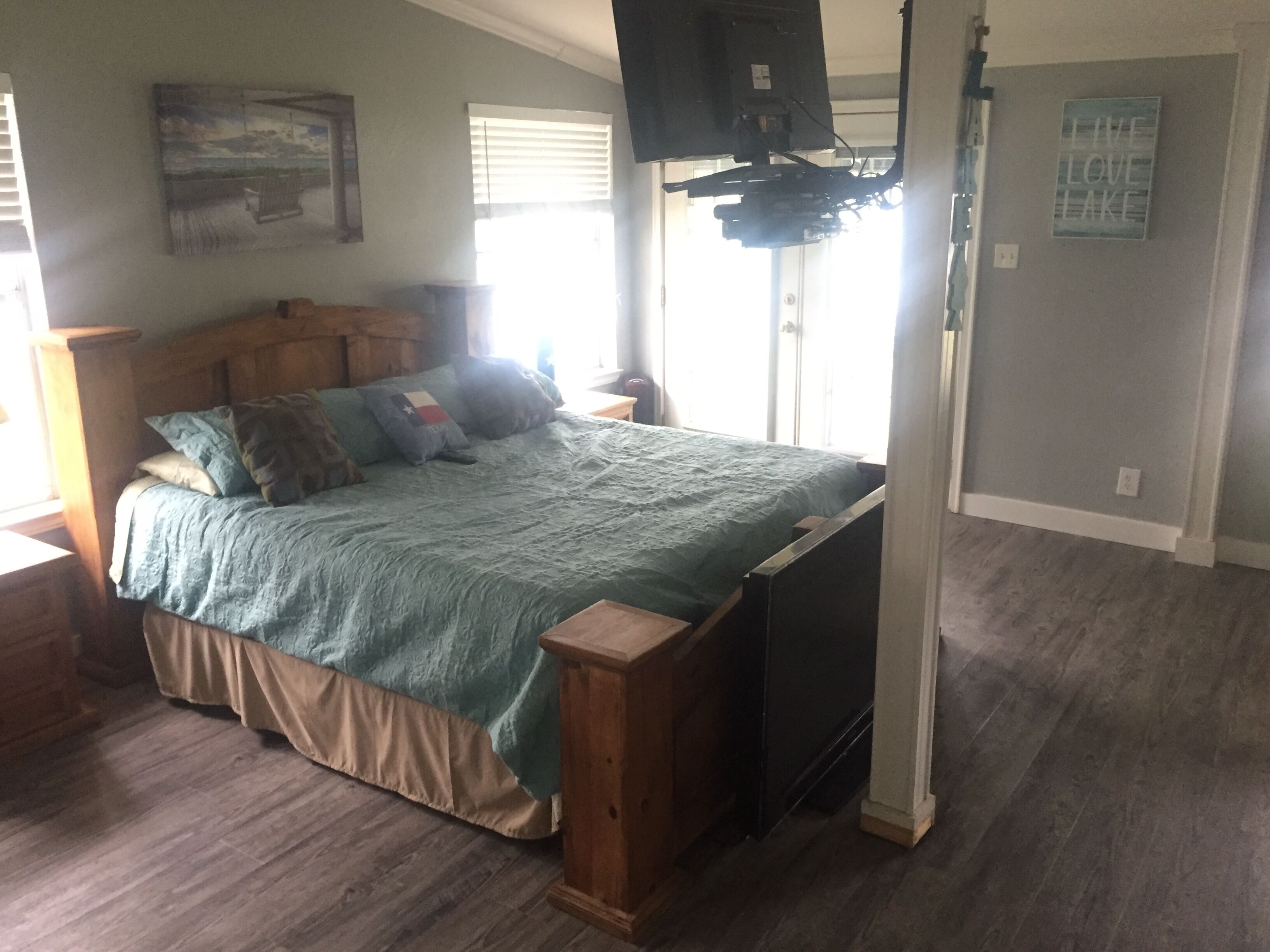 Ein Schlafzimmer mit einem Bett, einem Holz-Kopfteil und einem an der Wand montierten Fernseher.