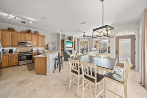 A spacious kitchen with wooden cabinets, a central island, and a dining area with a large table and chairs.