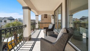 Un balcone con mobili in vimini, vista sulle case vicine e cielo sereno.