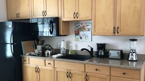 A kitchen with wooden cabinets, a black refrigerator, a sink, and various appliances.