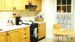 A kitchen with wooden cabinets, a stove, a coffee maker, and a table with chairs.