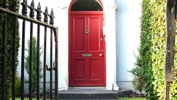 A red door with a small porch and a metal gate.