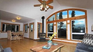 A spacious living room with a wooden table, a sofa, and a fireplace. - 3 Bedroom Home with Amazing Views 11 mi from Denal (Healy)