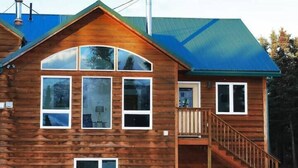 A wooden cabin with a steeply pitched roof, large windows, and a wooden staircase leading to a deck. - 3 Bedroom Home with Amazing Views 11 mi from Denal (Healy)