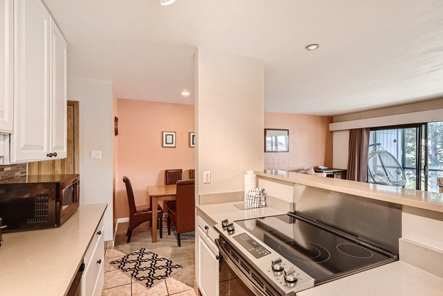 A modern kitchen with a large stove, dining area, and a view of the outdoors through a window.