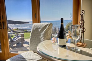 Enjoy ocean views from the room's large window, with a grassy area and wooden structures visible outside.