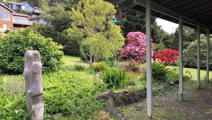 Ein Garten mit einem hölzernen Pfosten, einer überdachten Konstruktion und verschiedenen Pflanzen und Blumen.