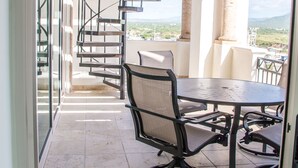 Un balcon doté d’un escalier en colimaçon, d’une table ronde et de chaises.