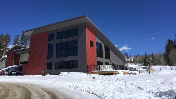 Un bâtiment moderne à la façade rouge et aux grandes fenêtres, entouré de neige.