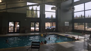Une piscine intérieure dotée de plusieurs couloirs, de grandes fenêtres et offrant une vue sur les arbres et les bâtiments environnants.